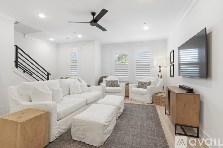 A living room with white furniture and a ceiling fan.