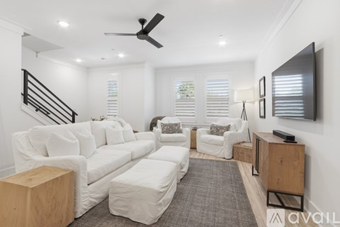 A living room with white furniture and a ceiling fan.