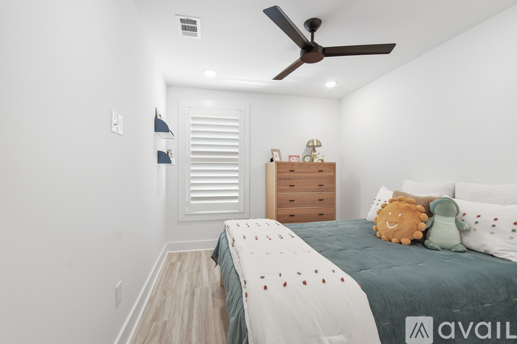 A bedroom with a bed, a dresser, and a ceiling fan.