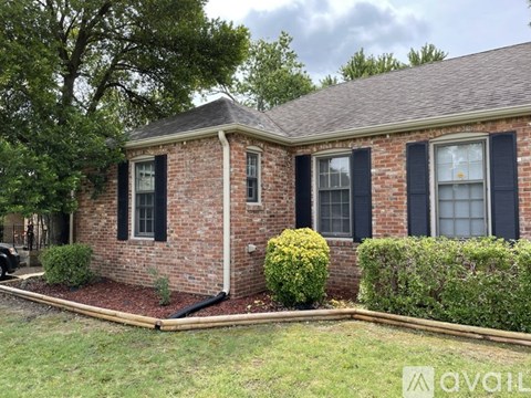 A brick house with black shutters and a small front yard.