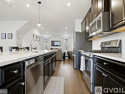 A modern kitchen with black cabinets and stainless steel appliances.