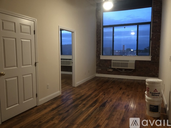 A room with wooden floors and a window overlooking a cityscape.