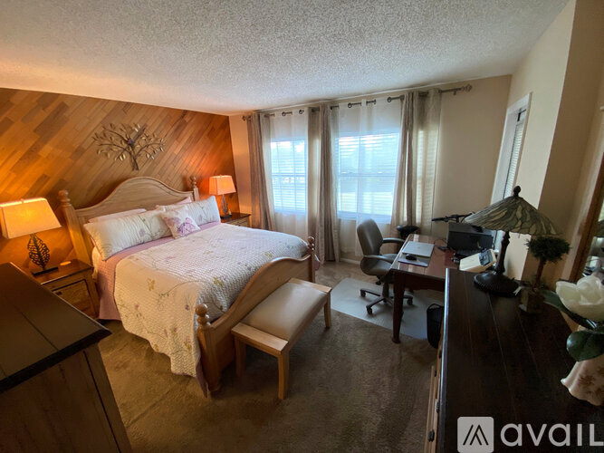 A bedroom with a bed, chair, and lamp.