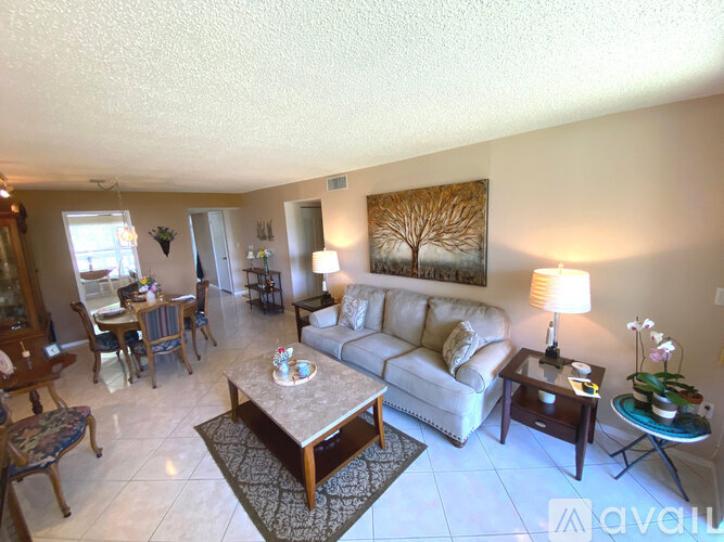 A living room with a couch, coffee table, and a painting on the wall.