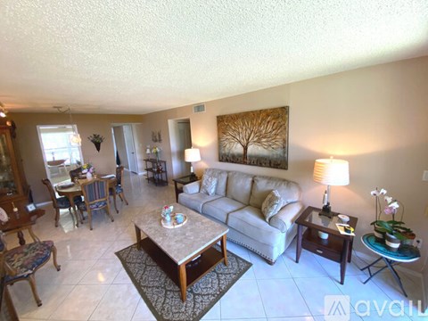 A living room with a couch, coffee table, and a painting on the wall.