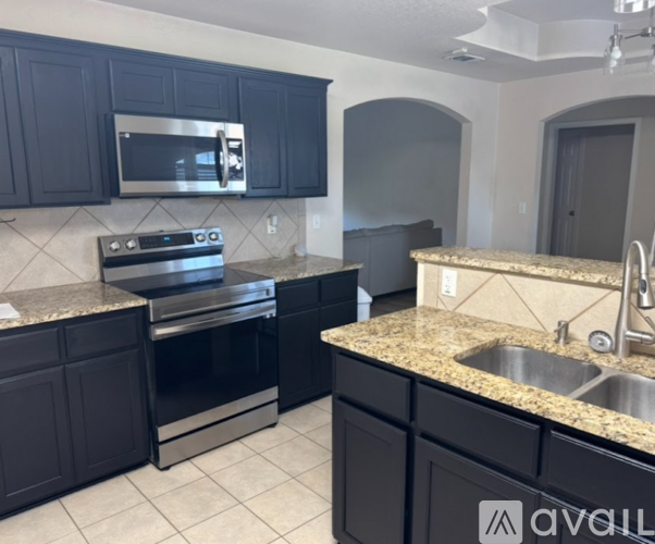 A kitchen with black cabinets and a granite countertop.