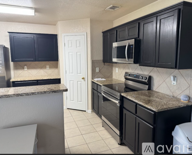 A kitchen with black cabinets and a granite countertop.
