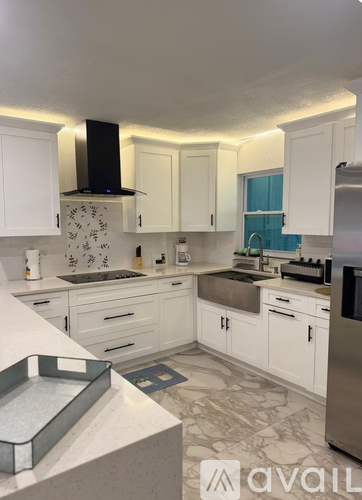 A kitchen with white cabinets and a stainless steel refrigerator.