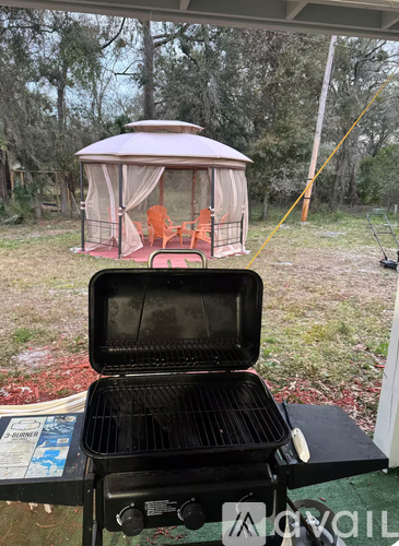 A grill is on a table outside with a gazebo in the background.