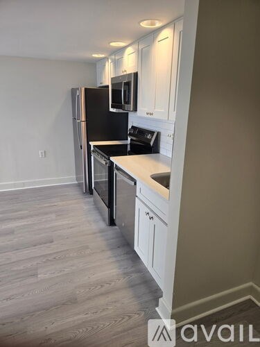A kitchen with a black fridge and white cabinets.