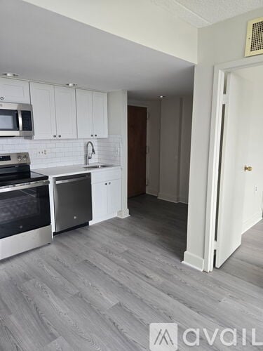 A kitchen with white cabinets and a grey floor.