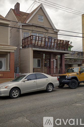 A silver car is parked in front of a house with a yellow jeep behind it.