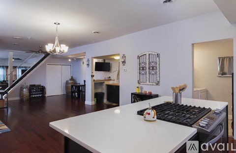 A kitchen with a white counter top and a staircase in the background.