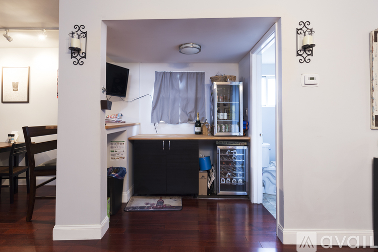 A kitchen area with a black fridge and a wooden table.