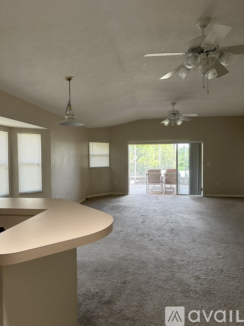 A spacious room with a carpeted floor and a ceiling fan.