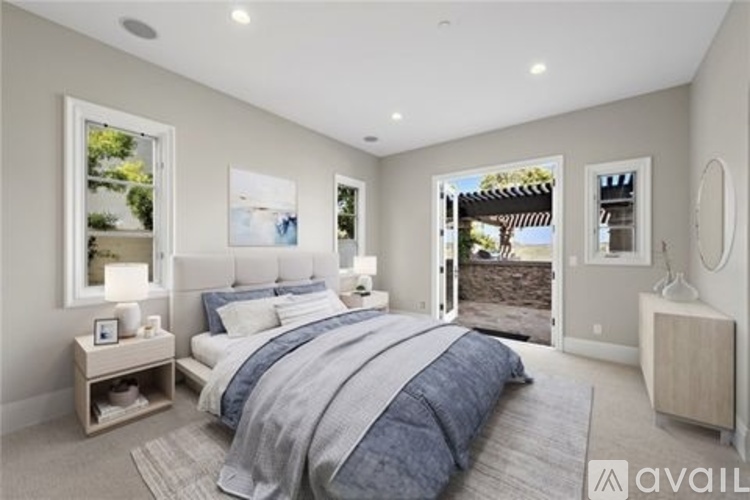 A bedroom with a large bed and a view of a backyard through the window.