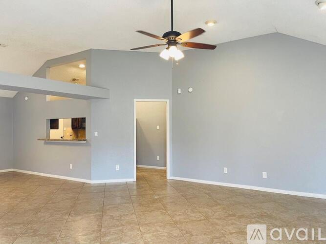 A spacious room with a ceiling fan and tiled flooring.