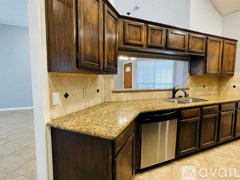 A kitchen with brown cabinets and granite countertops.