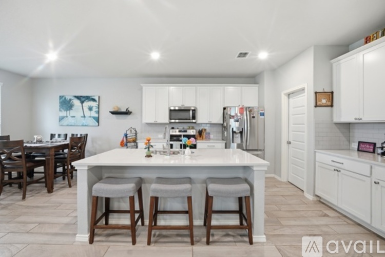 A kitchen with white cabinets and a large island with four stools.