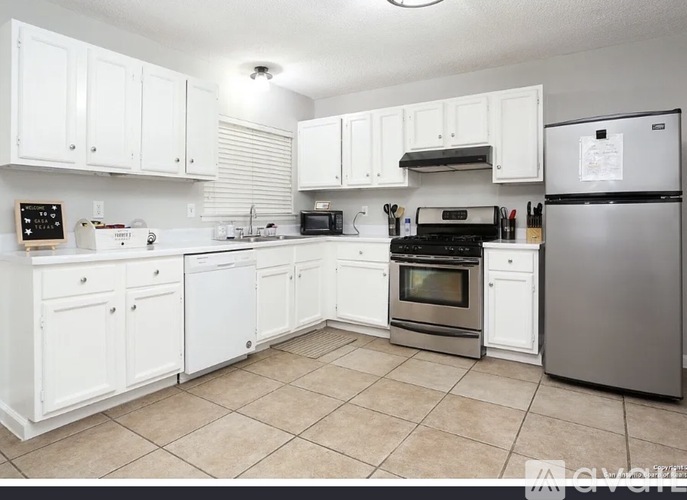 A kitchen with white cabinets and appliances.