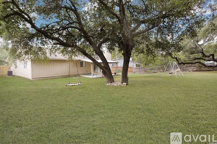 A tree stands in a grassy yard in front of a house.
