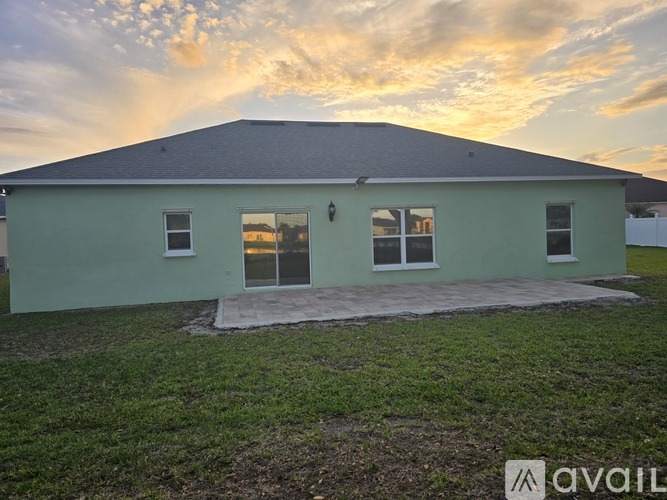 A house with a green exterior and a grey roof is shown with a sunset in the background.