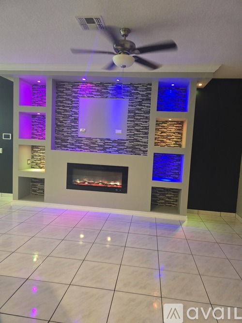 A modern living room with a fireplace and a ceiling fan.
