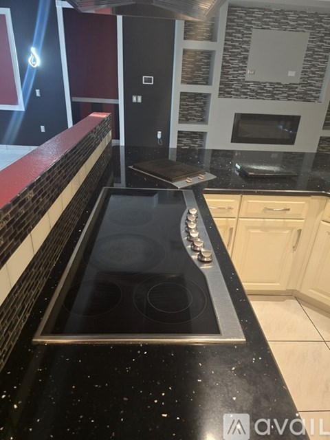 A modern kitchen with a black countertop and a stove top oven.