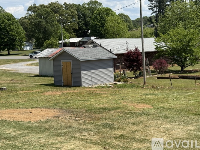A small grey building with a yellow door sits in a grassy field.