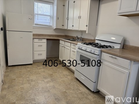 A kitchen with a white stove and cabinets, and a phone number on the wall.