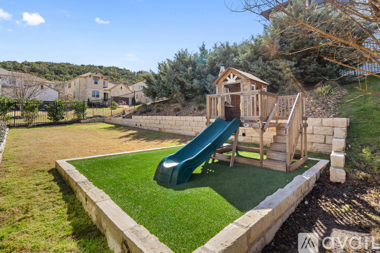 A playground with a green slide and wooden structure.