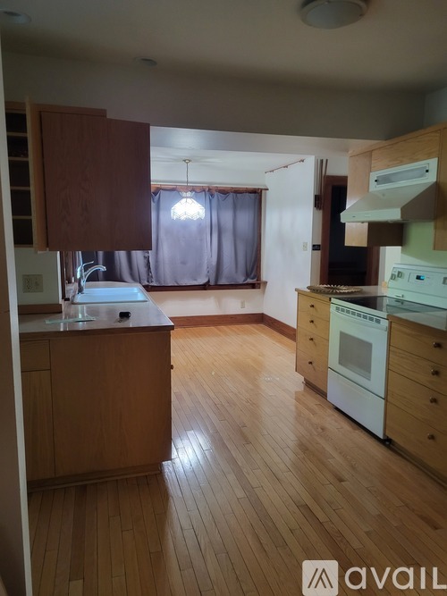 A kitchen with wooden floors and a window with curtains.