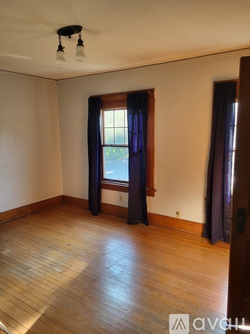 A room with wooden floors and a window with curtains.