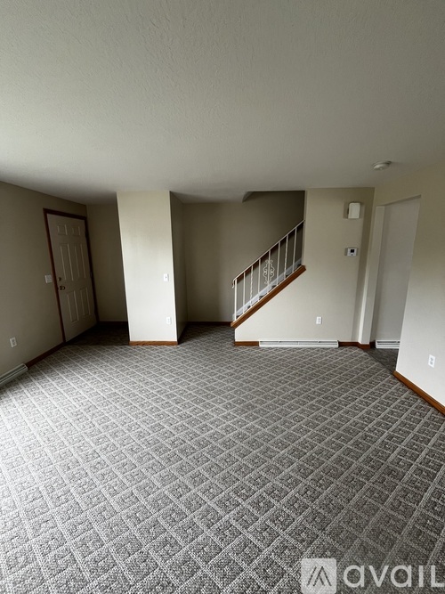 A room with a carpeted floor and a staircase.