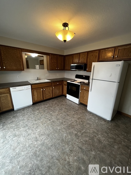 A kitchen with white appliances and wooden cabinets.