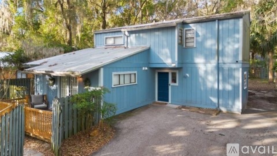 A blue house with a porch and a fence.