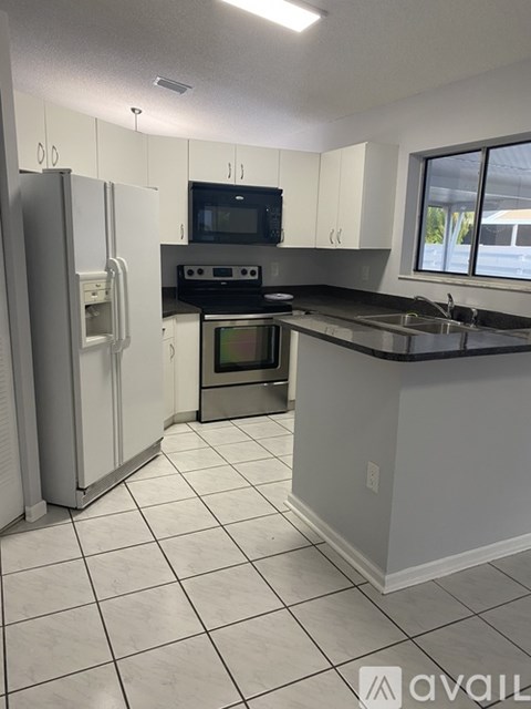 A kitchen with white cabinets and a black countertop.