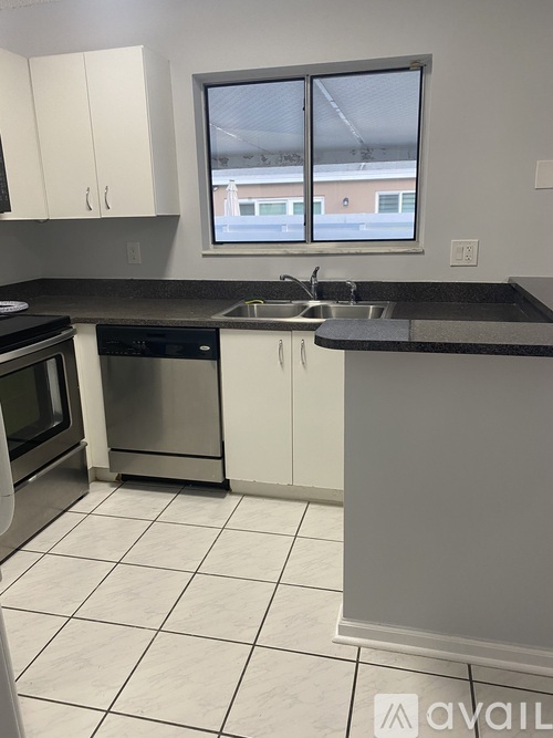 A kitchen with white cabinets and a black countertop.