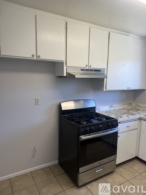 A black stove in a kitchen with white cabinets.