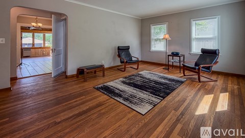 A living room with wooden floors and a rug in the center.