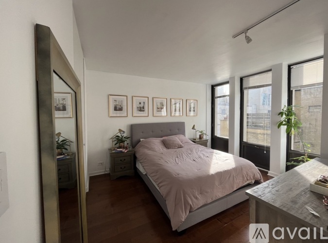 A bedroom with a large bed, a mirror, and a table with a plant on it.