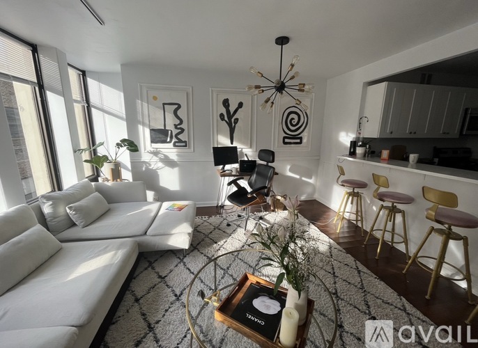 A living room with a white sofa, a coffee table with a record player, and a kitchen area in the background.