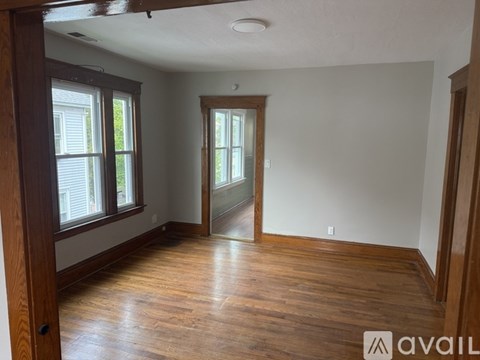 A room with wooden floors and a door leading to another room.
