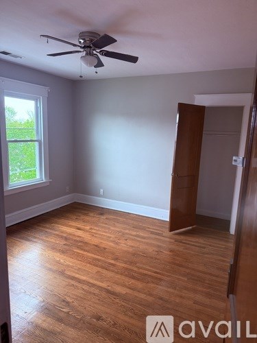 A room with a ceiling fan and wooden flooring.