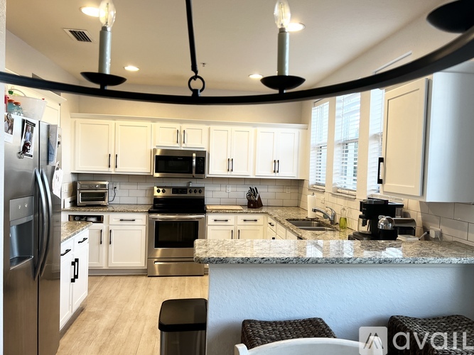 A kitchen with white cabinets and a marble countertop.