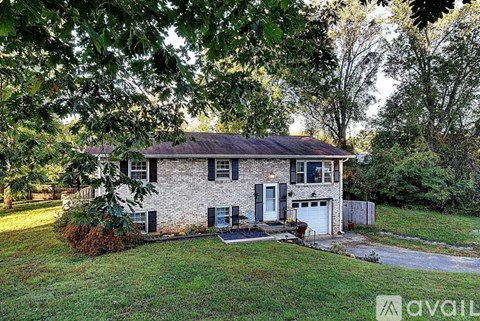 A house with a garage is surrounded by trees.