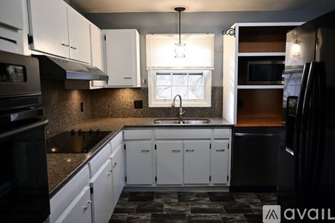 A kitchen with white cabinets and black appliances.
