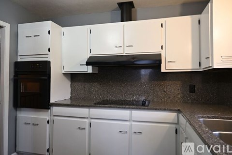 A kitchen with white cabinets and a black countertop.