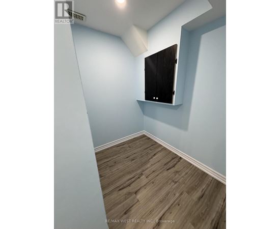A room with a wooden floor and a white wall with a black cabinet on it.