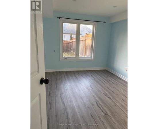 A room with light blue walls and wood flooring with a sliding glass door.